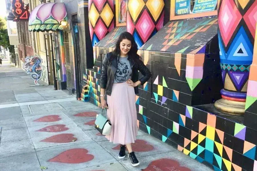 Una mujer se encuentra en una acera pintada con corazones rojos, frente a un colorido escaparate, en el barrio Haight-Ashbury de San Francisco.